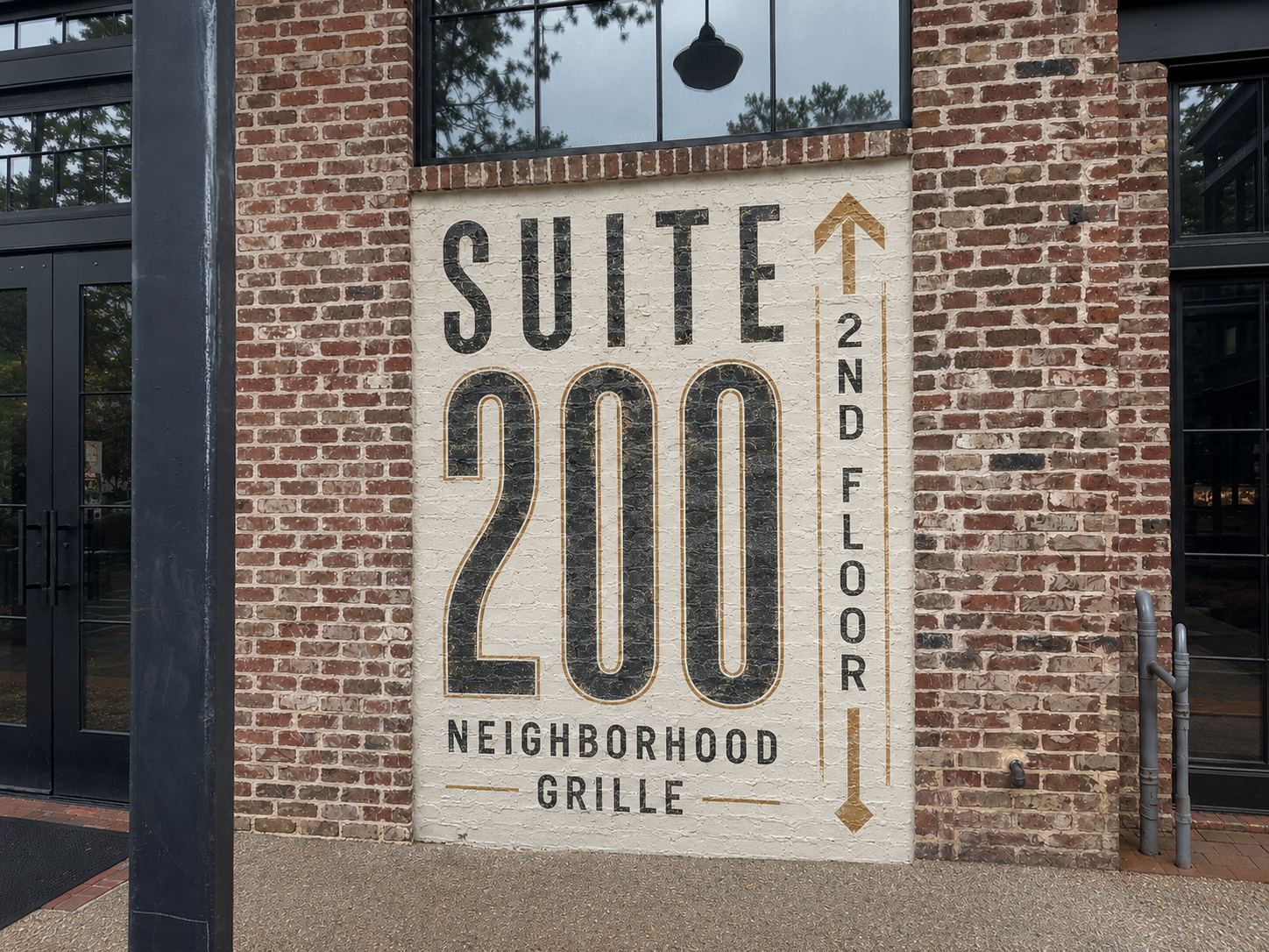 The hand-painted Suite 200 Neighborhood Grille sign on the brick exterior at 3000 Heritage Walk in Milton, Georgia